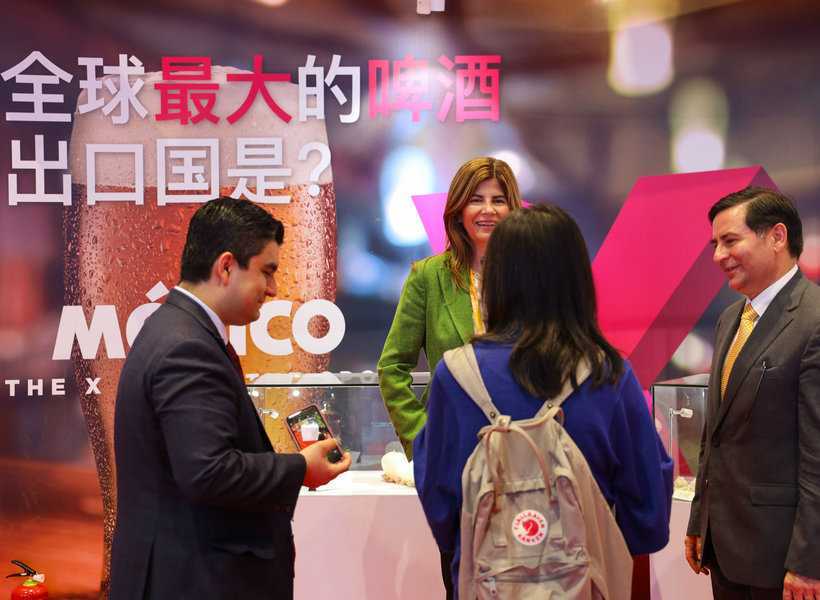 People talking at the Mexico Pavilion. The Chinese characters behind meaning "Which is the largest export country of beer in the world?"