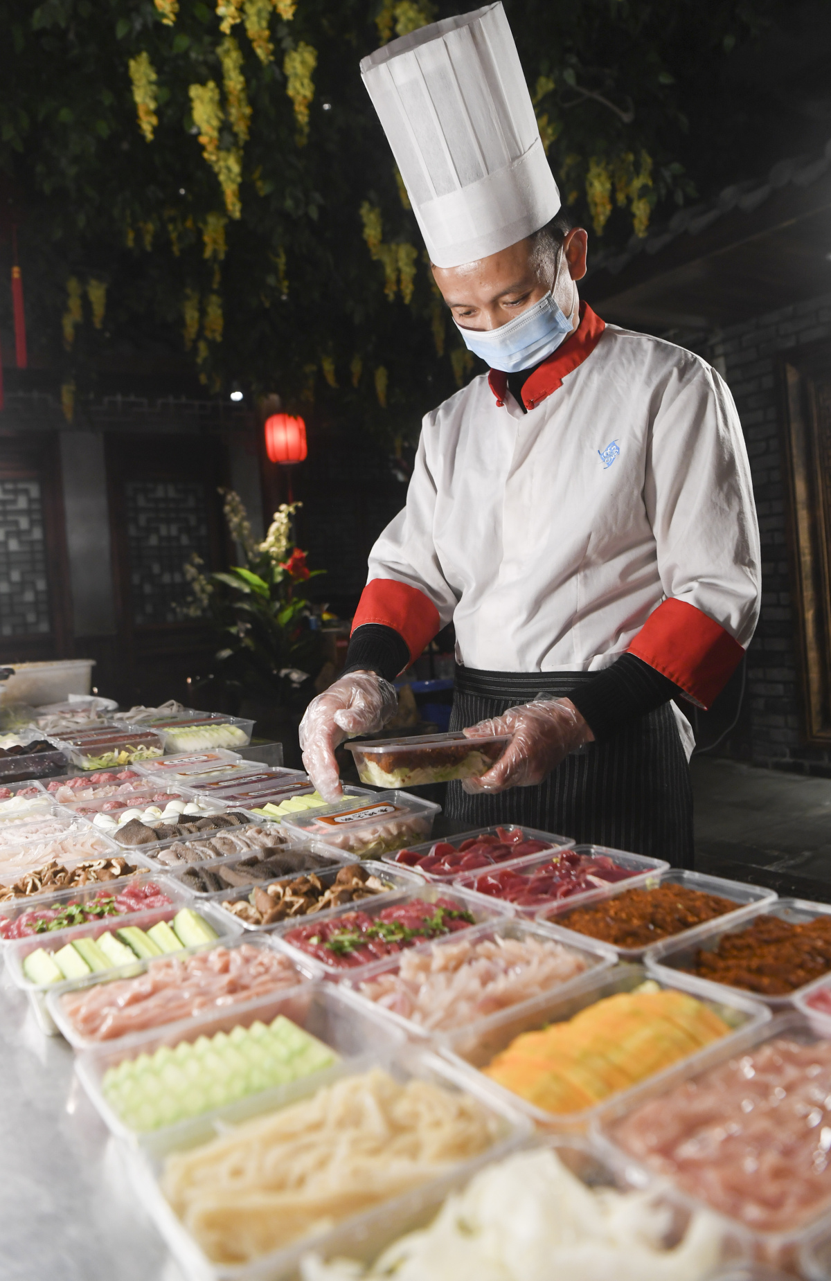 A cook from a hotpot restaurant in Chongqing prepares takeout food for online customers on Feb 15, 2020. (Wang Quanchao/Xinhua)