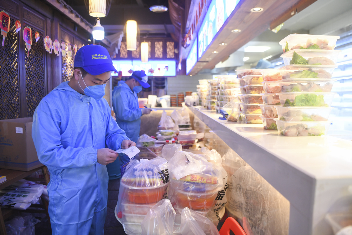Staff from a Chongqing hotpot restaurant checks orders for delivery on Feb 15, 2020. (Wang Quanchao/Xinhua)