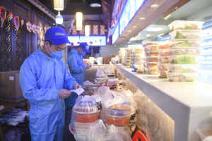 Staff from a Chongqing hotpot restaurant checks orders for delivery on Feb 15, 2020. (Wang Quanchao/Xinhua)
