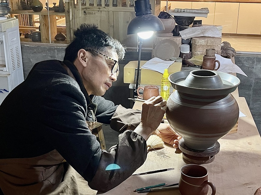 A pottery artist is painting on Rongchang pottery.