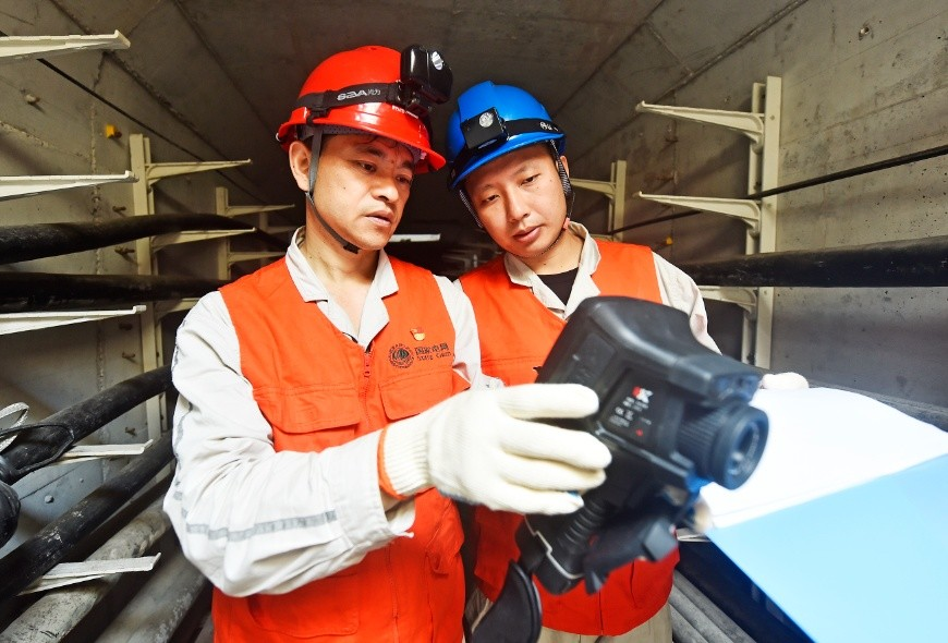 Workers use infrared thermometers to detect the operating temperature of cables and record.
