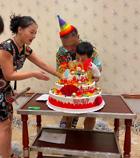 Baba and Ethan blow out the candles for the 80th birthday cake.