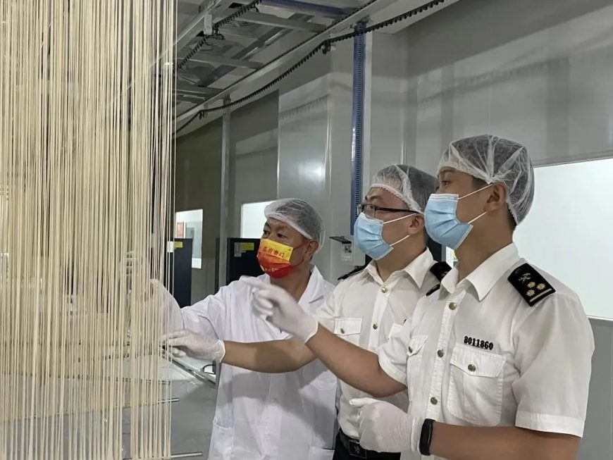 Chongqing Customs officers guide the worker during the processing of polygonatum noodles.